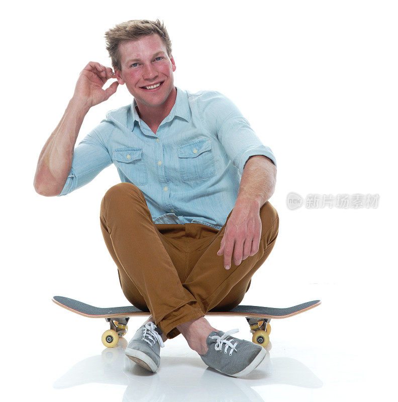 全长/一人20-29岁英俊的人/短发白人男性/年轻男子滑板/滑板/滑冰/坐/坐在地板前的白色背景穿纽扣衬衫/裤子